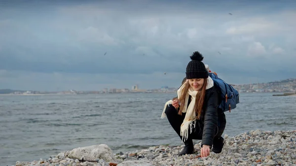 年轻的微笑的女人背着背包走在沙滩上寻找美丽的海贝壳 旅游和旅行的概念 — 图库照片