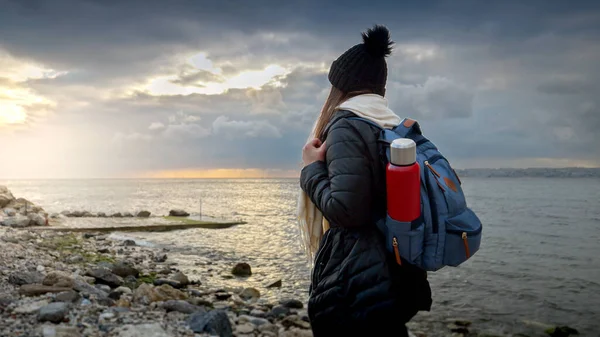 Жінка Ходить Теплому Одязі Рюкзаком Термосом Гуляючи Скелястому Морському Пляжу — стокове фото