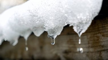 Çatıdaki buz saçaklarından düşen su damlacıklarını yakından çek. Mevsimleri değiştirmek, doğanın güzelliğini göstermek ve kıştan bahara geçiş.