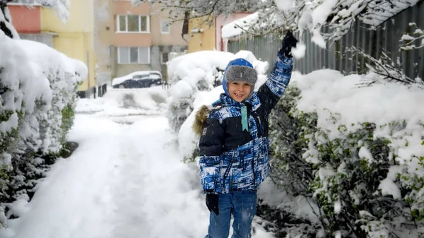 吹雪の後 陽気な笑顔の少年は木の枝から雪を振る 幸せな冬の休日 屋外で遊ぶ子供 冬の楽しみ — ストック写真