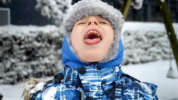 Portret Uśmiechniętego Chłopca Łapiącego Spadające Płatki Śniegu Otwartymi Ustami Językiem — Zdjęcie stockowe