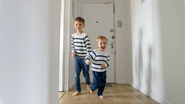 Två Små Pojkar Springer Med Leenden Trägolv Lång Korridor Hemma — Stockfoto