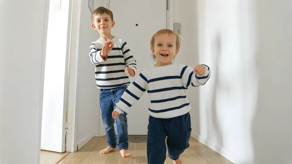 两个弟弟慢吞吞地跑过一条长长的木制走廊 他们的笑声和快乐闪烁着光芒 家庭和童年快乐的重要性 — 图库照片