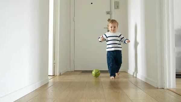 Mały Chłopiec Bawiący Się Piłką Drewnianej Podłodze Długiego Korytarza Swoim — Zdjęcie stockowe