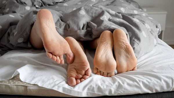 男男女女的脚套在柔软的床上 彼此轻抚着 家庭中的爱 感情和亲密的概念 — 图库照片