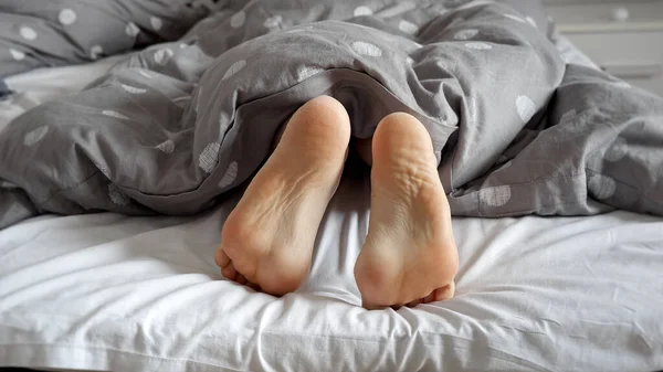 Zblízka Ženské Nohy Ležící Posteli Ukazující Zpod Přikrývky Žena Otáčí — Stock fotografie