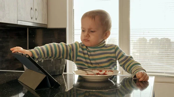 Mutfakta Çorba Içerken Tablet Bilgisayarda Çizgi Film Izleyen Küçük Üzgün — Stok fotoğraf