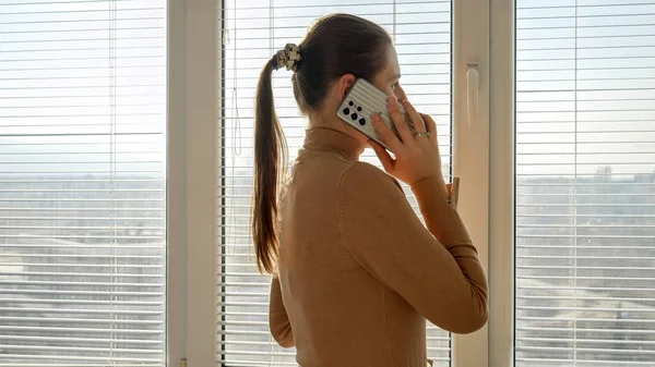 Wanita Muda Berbicara Melalui Telepon Jendela Dengan Tirai Saat Matahari — Stok Foto