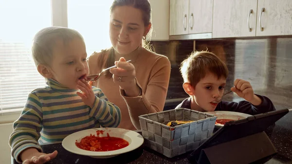 Giovane Madre Premurosa Che Nutre Suoi Due Figli Con Zuppa — Foto Stock