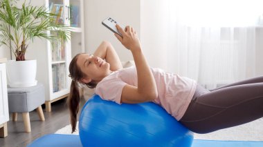 Genç bir kadın spor antrenmanlarını ve spor antrenmanlarını akıllı telefonuyla videoya çekiyor. Spor, spor ve yoga blogcuları ve etkileyiciler.