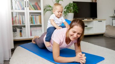 Tatlı erkek bebek, annelerin sırtında otururken o da beden eğitimi dersinde tahtada dikiliyor. Evde sağlık, spor ve yoga kavramı