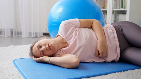 疲れた若い女性がフィットネスマットに横たわっており 自宅でのハードトレーニングの後 ほとんど呼吸 自宅での医療 スポーツ ヨガの概念 — ストック写真