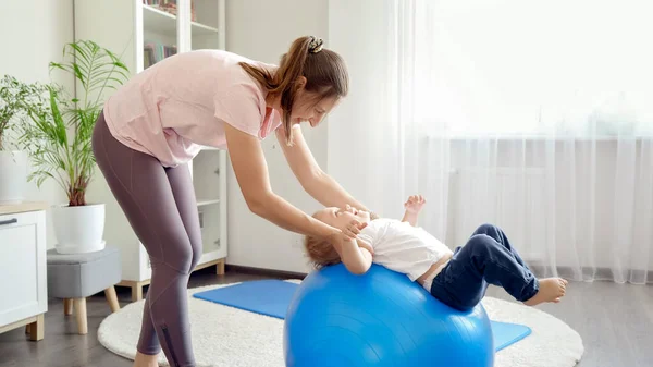 Felice Bambino Sorridente Rotolamento Sulla Palla Blu Fitness Con Madre — Foto Stock