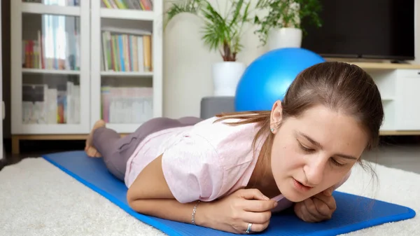 在健身训练期间做完木板后 年轻女子倒在健身垫上 家庭保健 体育和瑜伽的概念 — 图库照片