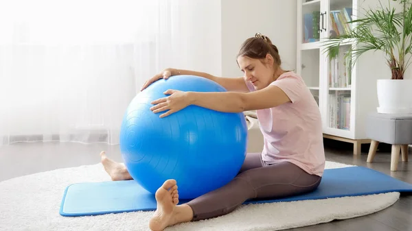 在健身训练前 微笑的女人伸展她的背部肌肉 并用热身球热身 家庭保健 体育和瑜伽的概念 — 图库照片