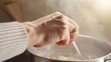 Çorbayı pişirirken esrarın içindeki malzemeleri karıştıran kadına yakın çekim. Sağlıklı beslenme, evde yemek pişirme, sıcak buhar
