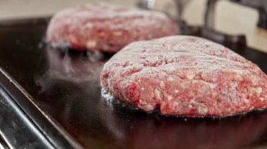 Izgara hamburger köftelerinden yakın çekim buhar geliyor. Evde yemek pişirme, mutfak aletleri, sağlıklı beslenme, hamburger malzemeleri.