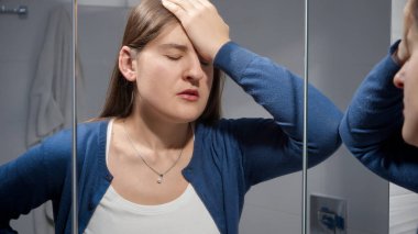 Hayattaki sorunlardan muzdarip üzgün bir kadın banyoda aynaya yaslanıyor. Depresyon, stres, zihinsel hastalık ve sorunlar, yalnızlık ve hüsran kavramı