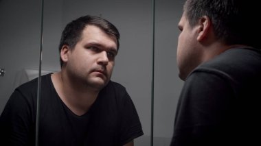 Depresyondaki genç adam aynada kendine bakıyor. Depresyon, intihar, stres, akıl hastalığı, yalnızlık ve hüsran kavramı