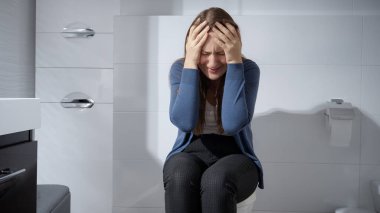 Genç üzgün kadın tuvalette tek başına oturup ağlıyor. Depresyon, ev içi şiddet, intihar, stres, yalnızlık ve hüsran kavramı