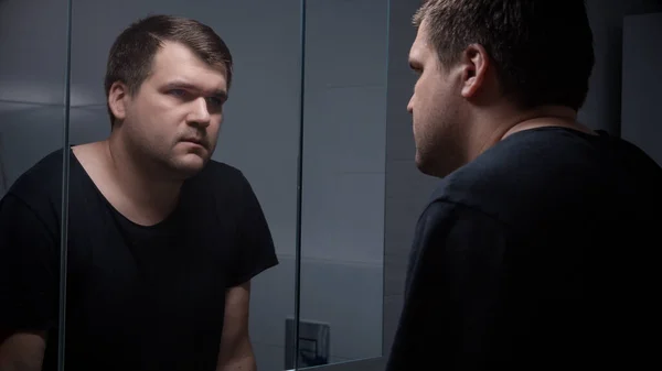 若い集中した男性は 鏡に映る彼の反射を見ている感情的な圧力を感じます — ストック写真