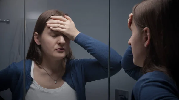 バスルームミラーで彼女の反射を見て動揺ストレスの女性 女性のうつ病や負の感情 — ストック写真