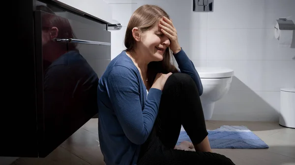 バスルームで床に座ってシンクにもたれて泣く女性 うつ病 家庭内暴力 ストレス フラストレーションの概念 — ストック写真