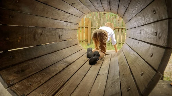 Mały Chłopiec Czołgający Się Czworaka Przez Drewnianą Rurkę Placu Zabaw — Zdjęcie stockowe
