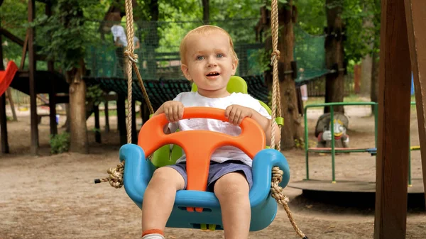 Glada Barn Pojke Ler Medan Svänger Färgglada Swing Lekplatsen Parken — Stockfoto
