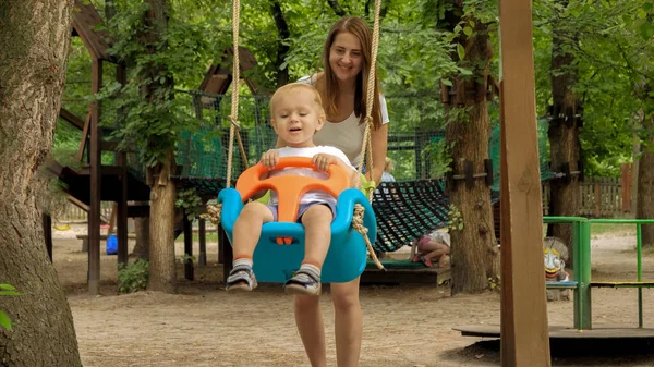 Feliz Madre Sonriente Con Niño Pequeño Balanceándose Columpio Colorido Parque — Foto de Stock