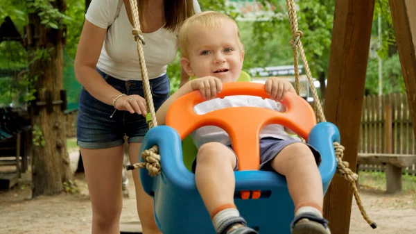 Menino Sorri Enquanto Sua Mãe Empurra Baloiço Colorido Playground Crianças — Fotografia de Stock