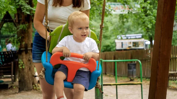 Glücklicher Kleiner Junge Mit Mutter Schaukelt Auf Dem Spielplatz Sommerpark — Stockfoto