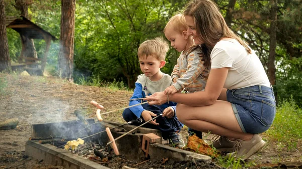 Young Mother Two Sons Cooking Sausages Bonfire Camp Active Leisure — Stock Photo, Image