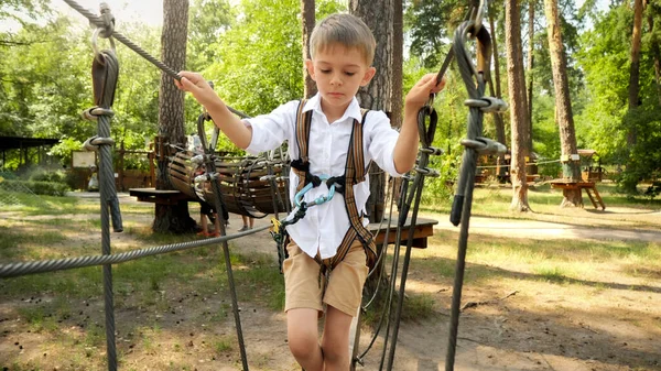 小さな男の子を慎重にケーブルや公園内の2つの木の間のロープを歩く アクティブな子供時代 健康的なライフスタイル 屋外で遊んでいる子供 自然の中で子供 — ストック写真
