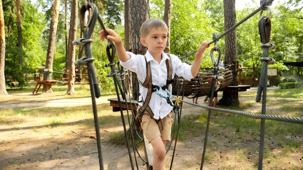 小さな男の子が屋外遊園地でロープブリッジを歩いています アクティブな子供時代 健康的なライフスタイル 屋外で遊んでいる子供 自然の中で子供 — ストック写真