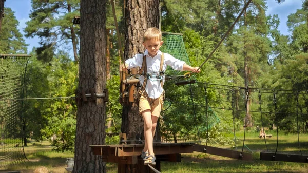男の子ロープで2本の木の間のケーブルを歩いて保持します アクティブな子供時代 健康的なライフスタイル 屋外で遊んでいる子供 自然の中で子供 — ストック写真