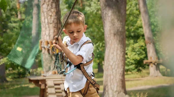 夏のキャンプでロープパークで楽しく極端な冒険をしている小さな男の子の肖像画 アクティブな子供時代 健康的なライフスタイル 屋外で遊んでいる子供 自然の中で子供 — ストック写真