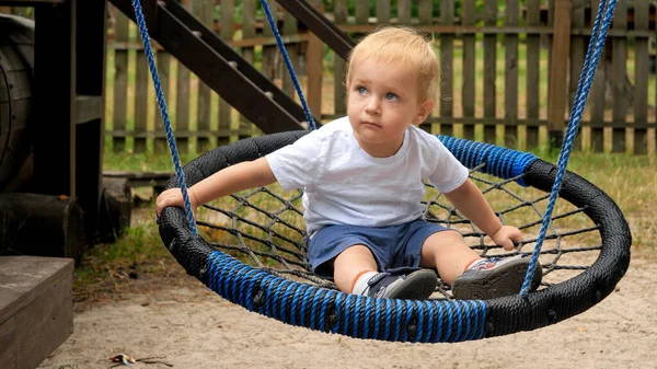Glücklich Lächelnder Kleiner Junge Der Einer Nestschaukel Auf Dem Spielplatz — Stockfoto
