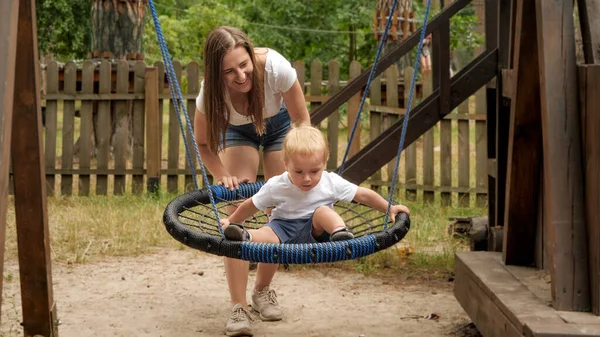 Risa Madre Empujando Hijo Pequeño Balanceándose Patio Juegos Parque — Foto de Stock