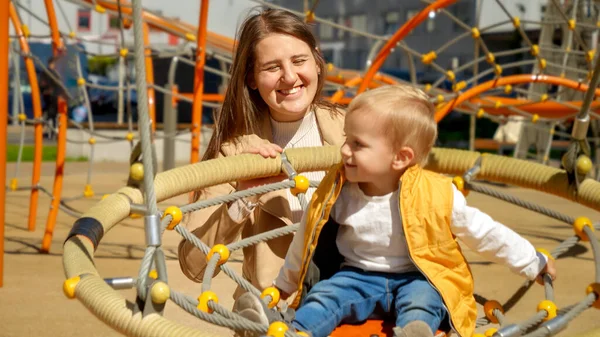 Portret Szczęśliwej Uśmiechniętej Matki Huśtającej Synka Placu Zabaw Słoneczny Dzień — Zdjęcie stockowe