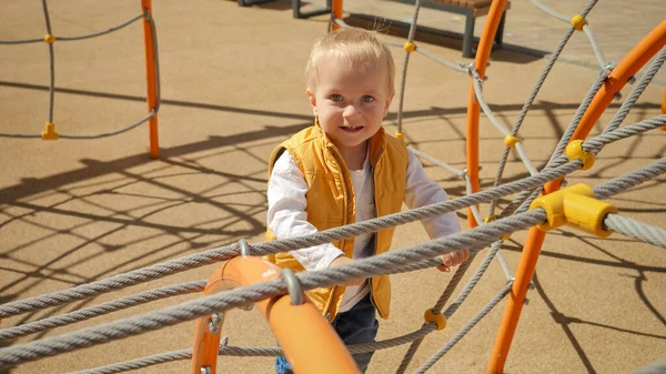 Aranyos Vidám Kisfiú Portréja Amint Felmászik Kötélhágcsóra Játszótéren Gyerekek Kültéri — Stock Fotó