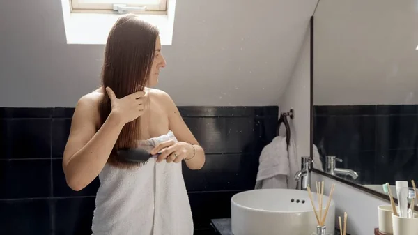 Žena Zabalená Ručníku Stojící Vaně Upravující Dlouhé Vlasy Před Zrcadlem — Stock fotografie
