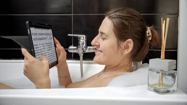 Woman Combines Bath Time with Tablet Computer. Working at home, modern technology, remote job.