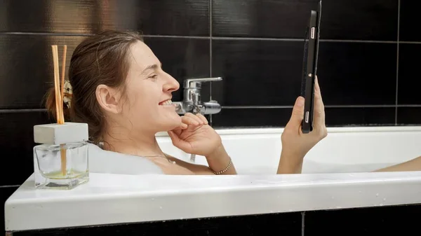 タブレットパソコンでビデオ通話をしながらお風呂に入る女性 セルフケアを最優先しながら 私たちがつながる現代的な方法を紹介するのに最適です — ストック写真