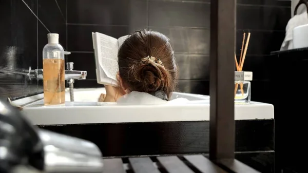 Lginç Bir Kitapla Banyoda Rahatlayan Zarif Bir Kadının Arka Görüntüsü — Stok fotoğraf