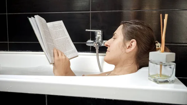 本と一緒にお風呂に入るブルネットの女性の肖像 セルフケア — ストック写真
