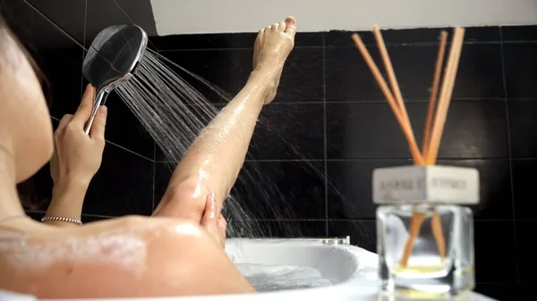 一位女性沉溺于温泉般的体验 在温和的淋浴下轻松地洗澡和洗脚 促进自我照顾和放松 — 图库照片