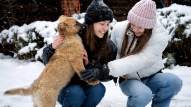 Köpekli iki mutlu kız evin arka bahçesinde karda eğleniyor. Hayvanlı çocuklar, evcil hayvanlarla oyunlar