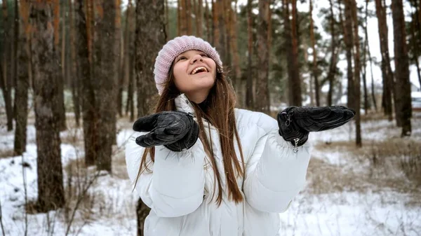 在冬天的森林里 一个笑得很开心的少女牵着手滑落在地上的雪花 — 图库照片