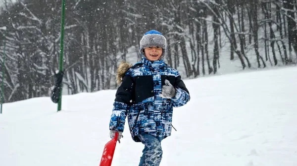 Радісний Хлопчик Піднімається Засніжений Пагорб Сідлами Руці Готовий Насолоджуватися Зимовими — стокове фото